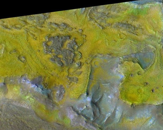 A close-up view of the eroded terrain in Nili Fossae using a CRISM infrared image to colorize a high-resolution HiRISE camera image. Beneath a rough-textured capping rock unit (purple) are banded olivine-bearing layers (yellow) which in some places have been partially altered to carbonate (bright green).
